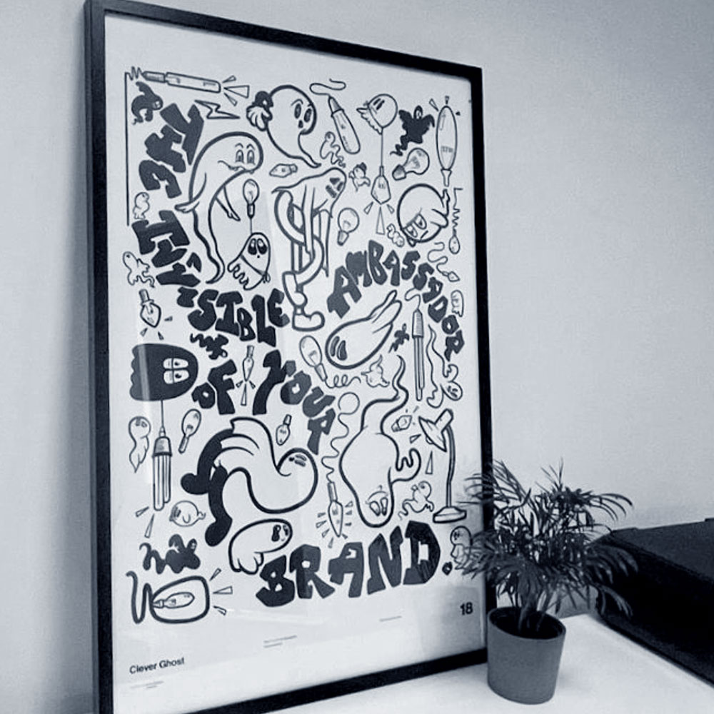 A framed black and white Clever Ghost brand illustration on a studio wall