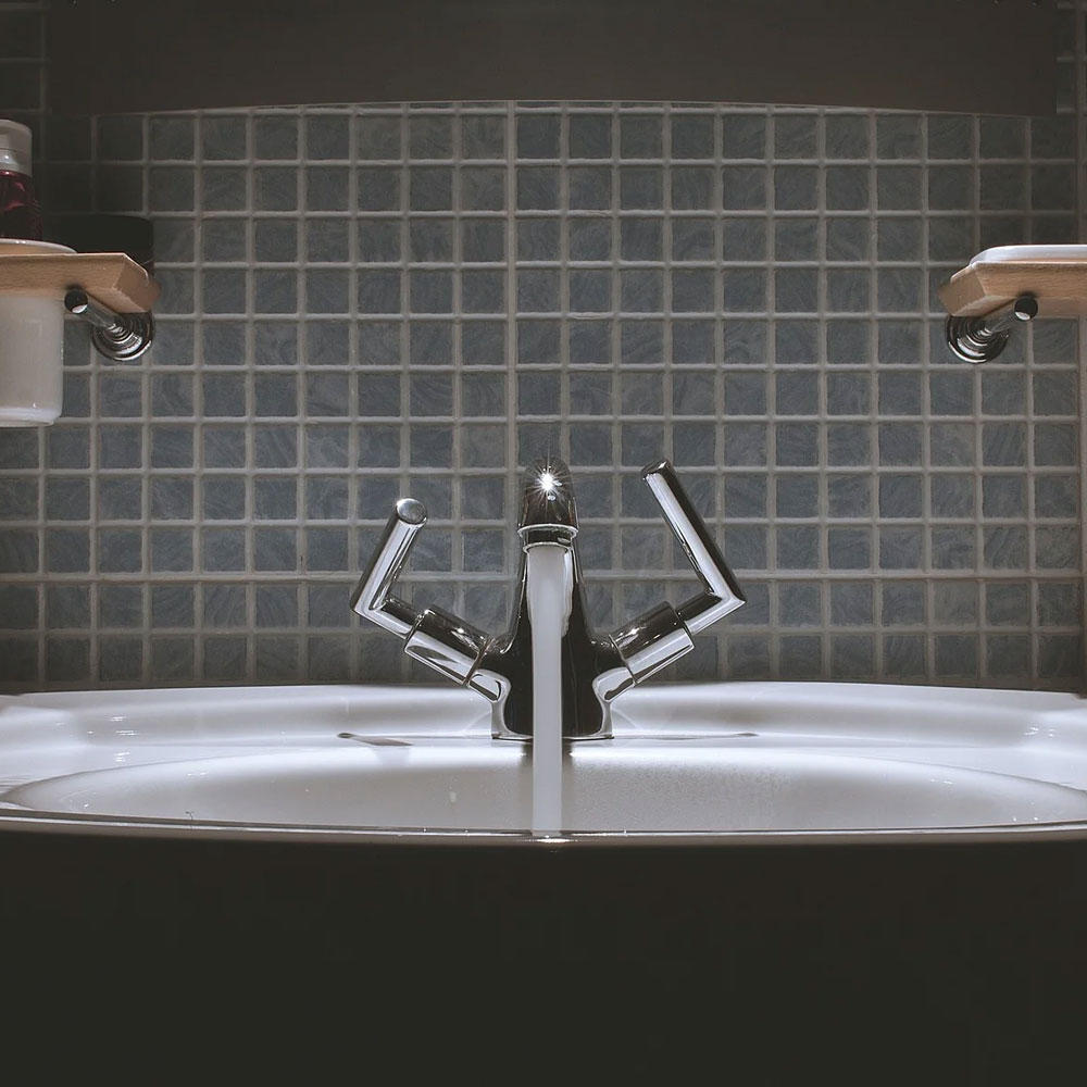 A tiled bathroom with a basin and mixer tap