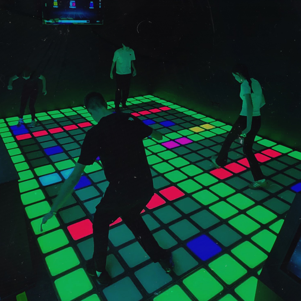 A player on the illuminated interactive games floor at Tactixs