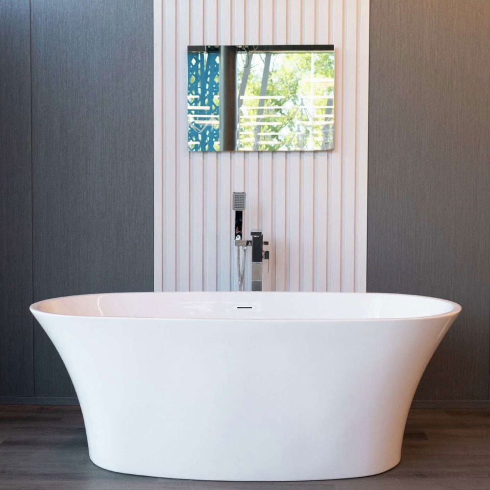 A freestanding bath beneath a window in a tiled bathroom